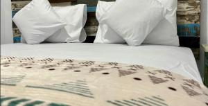 a bed with white sheets and pillows at Surabaya Vibes Hostel in Surabaya
