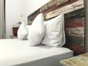 a bed with white pillows against a wooden headboard at Surabaya Vibes Hostel in Surabaya