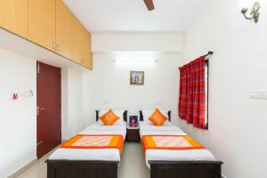 a room with three beds with orange pillows at Starlight Hotels OMR Thoraipakkam in Chennai