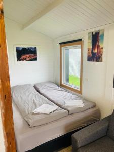 a bed in a small room with a window at Vestra Fíflholt Cabin 4 in Hvolsvöllur