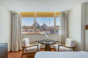 a bedroom with a bed and chairs and a table and a window at Superior Pyramids View in Cairo