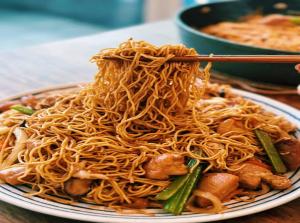 a plate of noodles on a table with chopsticks at Sky Nest Plaza Inns Near Delhi International Airport in New Delhi