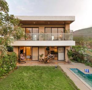 a house with a view of the backyard at Saffron Stays Augustus in Karjat