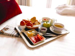 a tray of food on a bed with a plate of food at Mercure Limoges Centre in Limoges