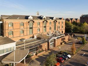 a large brick building with cars parked in a parking lot at Novotel Cardiff Centre in Cardiff