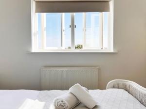 a bed with a window with a towel on it at Spinney's Boathouse by The Suffolk Cottage Collection in Thorpeness