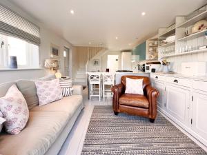 a living room with a couch and a kitchen at Spinney's Boathouse by The Suffolk Cottage Collection in Thorpeness +12 photos