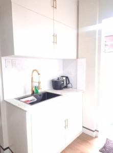 a kitchen with white cabinets and a sink at JAL Transient House in Hinoba-an