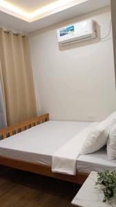 a bedroom with a bed with a air conditioner on the wall at JAL Transient House in Hinoba-an