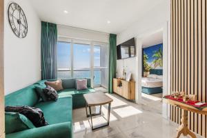 a living room with a green couch and a bedroom at The Butterfly Apartment | Seafront & Amazing Views by PikHost in Lezhë