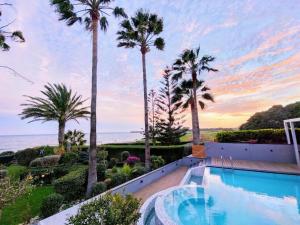 a villa with a swimming pool and palm trees at Villa Del Mar with Heated Pool & Spa in Mazotos