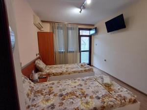 a bedroom with two beds and a television in it at Апартаменти и стаи Анхиало in Pomorie
