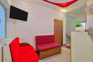a room with two red chairs and a tv at Via KR in Chennai