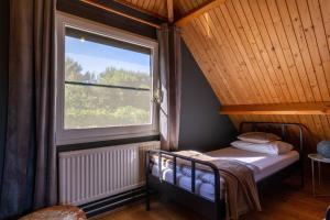 a bedroom with a bed and a large window at Veerse Meer Lodge in Wolphaartsdijk