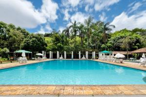a large swimming pool with chairs and umbrellas at Studio in Condo w/ Pool in Downtown QUI0605 in Poços de Caldas