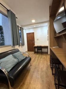 a living room with a leather couch and a table at STUDIO Flat B in Betim