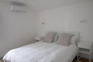 a white bed with white sheets and pillows at Villa Serena - Armonia Apartment in Tirrenia