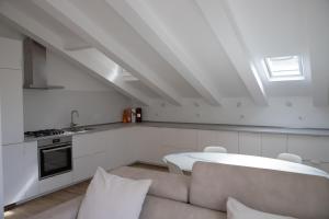 a white living room with a couch and a kitchen at Villa Serena - Armonia Apartment in Tirrenia
