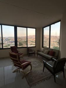 a living room with chairs and a couch and large windows at Ranachalet-1 in Ash Shāghūr