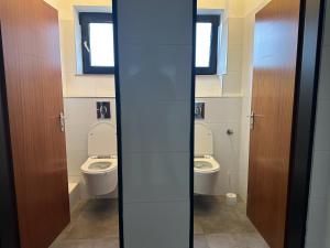 a bathroom with two toilets and two windows at Boberger Hostel in Hamburg