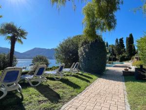 a row of lounge chairs sitting on the grass by the water at Appartamento Pascià al Lago in Oggebio