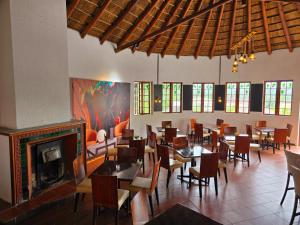 a restaurant with tables and chairs and a fireplace at Beverly Hills Lodge in Fourways