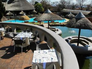 a pool with tables and umbrellas next to a resort at Beverly Hills Lodge in Fourways +24 photos