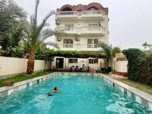 a person swimming in a swimming pool in front of a building at Villa Set ma'at Nile view in Luxor