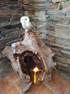 an owl sitting on top of a tree stump with a candle at Albergue Val de Samos in Samos