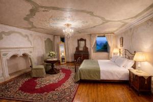 a bedroom with a large bed and a chandelier at Villa De Rubeis Florit in Tarcento