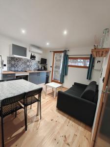 a living room with a black couch and a kitchen at Cier De Riviere "les Ours" in Cier-de-Rivière +26 photos