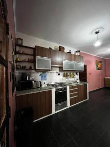 a kitchen with brown cabinets and a pink wall at casa cusi in Tafí Viejo