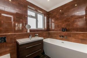 a bathroom with a tub and a sink and a bath tubermottermott at Luxury Beach Escape Pool Table & Private Parking in Broadstairs +14 photos