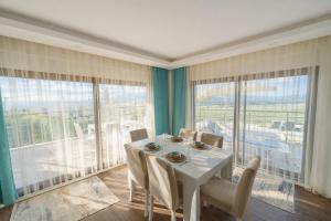 a dining room with a white table and some windows at Villa Everest in Dalaman