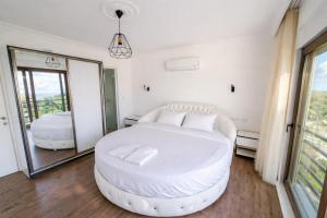 a bedroom with a white bed and a mirror at Villa Everest in Dalaman