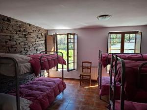 a room with three bunk beds with purple blankets at Albergue Val de Samos in Samos