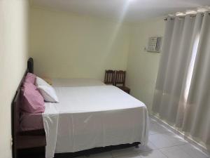 a bedroom with a white bed and a window at Condomínio Il Sole - apartamento 1 in Porto Seguro