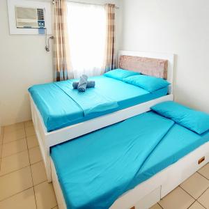 a bedroom with two beds with blue sheets at Nanay's Condotel in Sampong +8 photos
