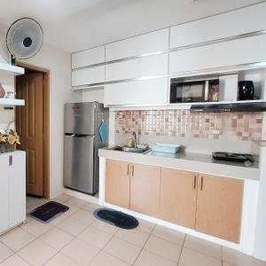 a kitchen with white cabinets and a stainless steel refrigerator at Nanay's Condotel in Sampong