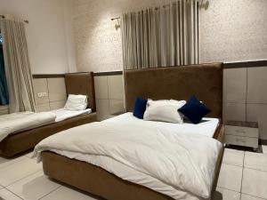 a bedroom with two beds with white and blue pillows at Primrose Hotel in Murthal