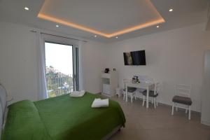 a white bedroom with a green bed and a table at Amalfi Montemare Rooms in Amalfi