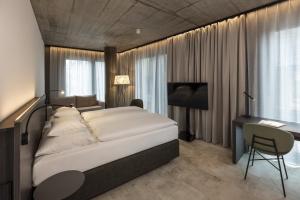 a bedroom with a bed and a desk and a computer at ARCOTEL Tabakfabrik Linz in Linz