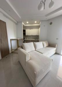 a living room with a white couch and a kitchen at Apartment with sea view and pool access in Chott Meriem