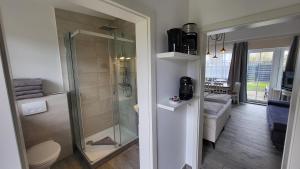 a bathroom with a glass shower and a living room at Hotel Schleimünde in Kappeln +57 photos