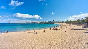 a group of people on a beach near the water at Casita Malvika - Luxury and Sea view - 1min to the Beach By Lanzarote Vacation Homes in Costa Teguise