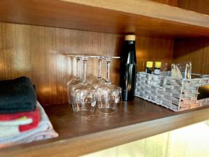 three wine glasses and a bottle on a shelf at Wilderness Retreat in Alba