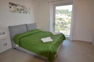 a bedroom with a green bed with a window at Amalfi Montemare Rooms in Amalfi