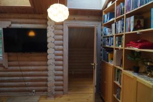a room with book shelves with a television and a door at The Log Cabin in Hadsund