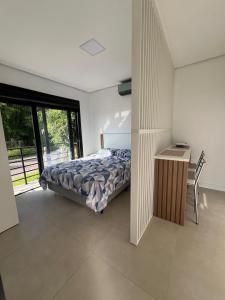 a bedroom with a bed and a desk and a window at Suíte completa com cozinha e hidromassagem in Torres