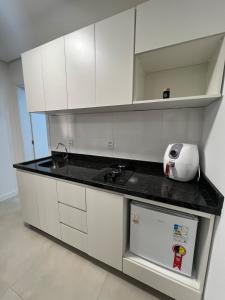 a kitchen with white cabinets and a black counter top at Suíte completa com cozinha e hidromassagem in Torres